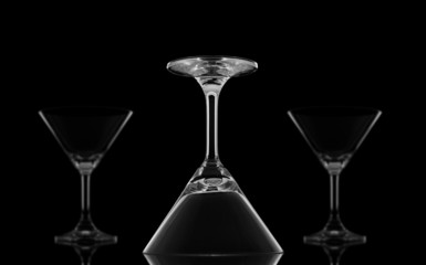 Cocktail glasses upside down on black background and reflection