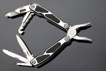 Steel pliers folding multi tool opened on gray background
