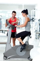 woman on stationary bicycle with personal trainer