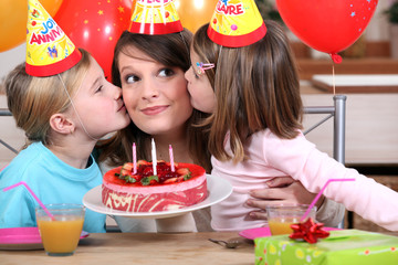 sisters kissing mom at birthday's party
