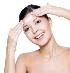 happy woman applying cosmetic cream on forehead