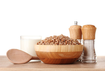 Boiled buckwheat in a wooden bowl with a glass of milk