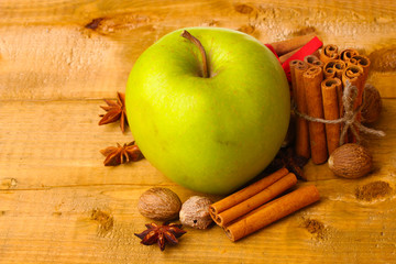 Cinnamon sticks, green apple, nutmeg,and anise on wooden table