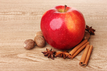 Cinnamon sticks,red apple, nutmeg,and anise on wooden table