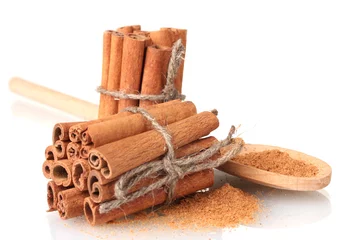 Rolgordijnen Cinnamon sticks and powder in wooden spoon isolated on white © Africa Studio