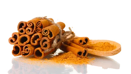 Fototapeten Cinnamon sticks and powder in wooden spoon isolated on white © Africa Studio