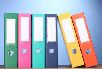 bright office folders on wooden table on blue background