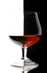 Glass of cognac on white-black background