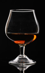 Glass of cognac on black background