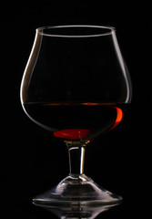 Glass of cognac on black background