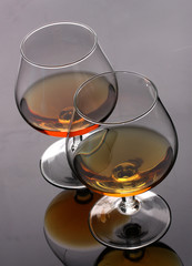 Two glasses of cognac on grey background