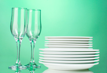 Clean plates and glasses on green background
