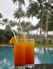 Two Glasses of Tequila Sunrise by a Pool