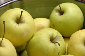Yellow and green Golden apples in a green bowl.