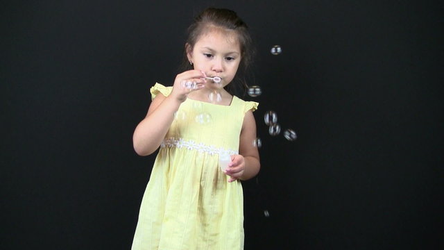 child blowing bubbles in studio