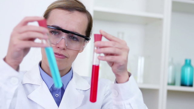 scientist comparing test tubes with red and blue substance