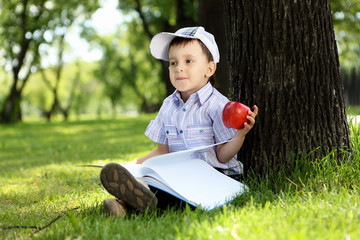 Portrait of a boy with a book in the park