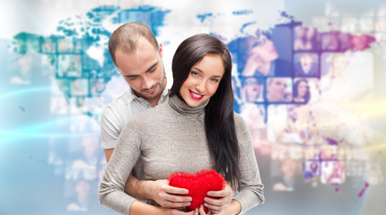 Portrait of young couple embracing and holding red heart. Standi