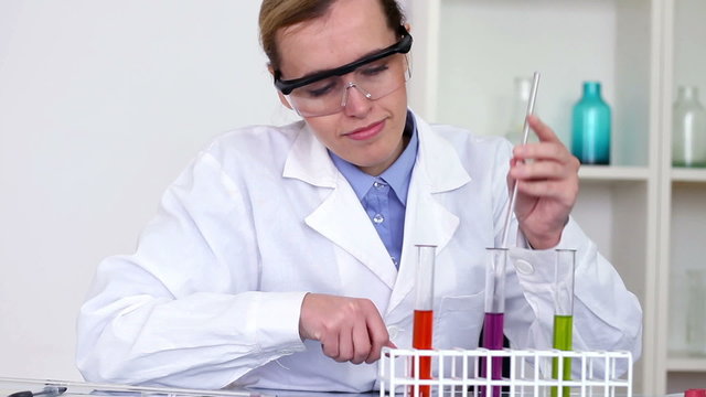 scientist mixing chemicals in test tubes with stirring rod