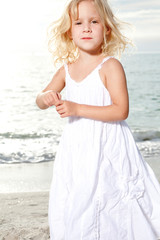 Fototapeta na wymiar Little girl enjoys sunny day at the beach.