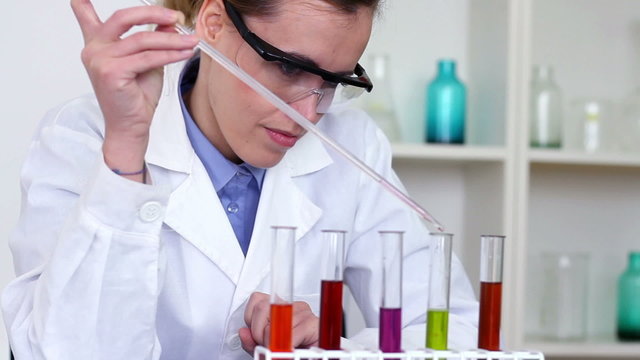 Scientist using pipette to add substance to test tubes