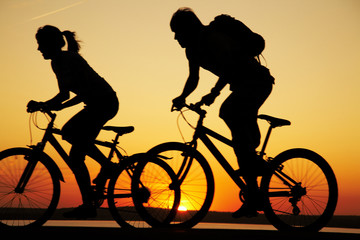 Obraz premium Young couple riding bicycles at sunset