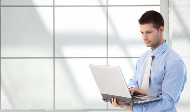Young professional using laptop in office lobby