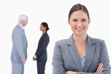 Smiling businesswoman with folded arms and colleagues behind her