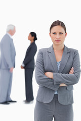 Serious businesswoman with arms folded and colleagues behind her
