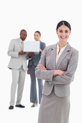 Smiling tradeswoman with folded arms and co-workers behind her