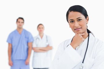 Fototapeta premium Thoughtful doctor with colleagues behind her