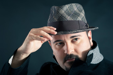 Confident man portrait with hat on dark background.