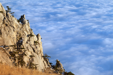 Fototapeta na wymiar Sunlit cliffs and sea in clouds
