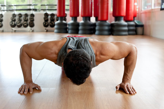 Muscular man doing push-ups - Powered by Adobe