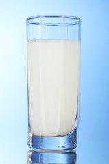 Tasty milk in glass on blue background
