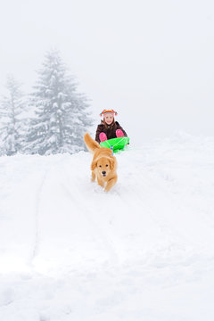 dog pulling child down a hill in winter snow