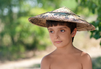Boy in Vietnamese hat is looking sideways