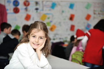 Happy little girl in school with her friends arround