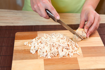 Cutting of chicken meat on a finishing kitchen board