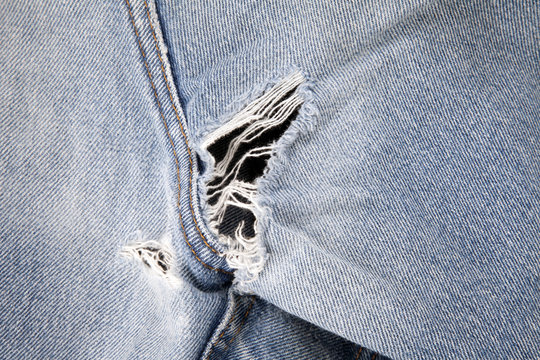 Close up of hole in an old pair of blue jeans