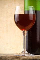 glass of red wine and bottle on wood background