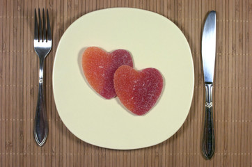 Golosinas con forma de corazón dentro de un plato, cubiertos.