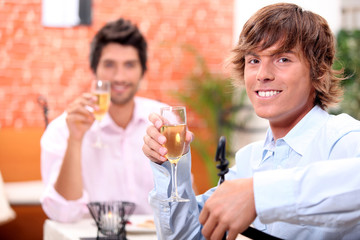 Two businessmen drinking champagne in restaurant