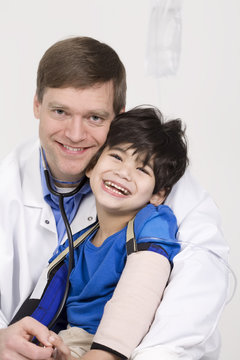 Male doctor holding five year old disabled patient