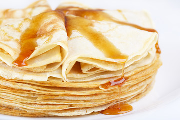 A stack of thin pancakes with honey