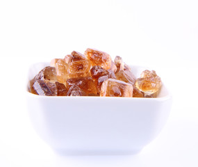 Brown rock candy in a bowl on a white background