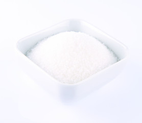 White sugar in a bowl on a white background