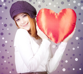 Beautiful red-haired girl in cap with toy heart.