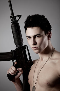Handsome bare-chested soldier is holding a rigle