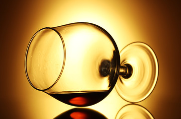 Glass of cognac on yellow background